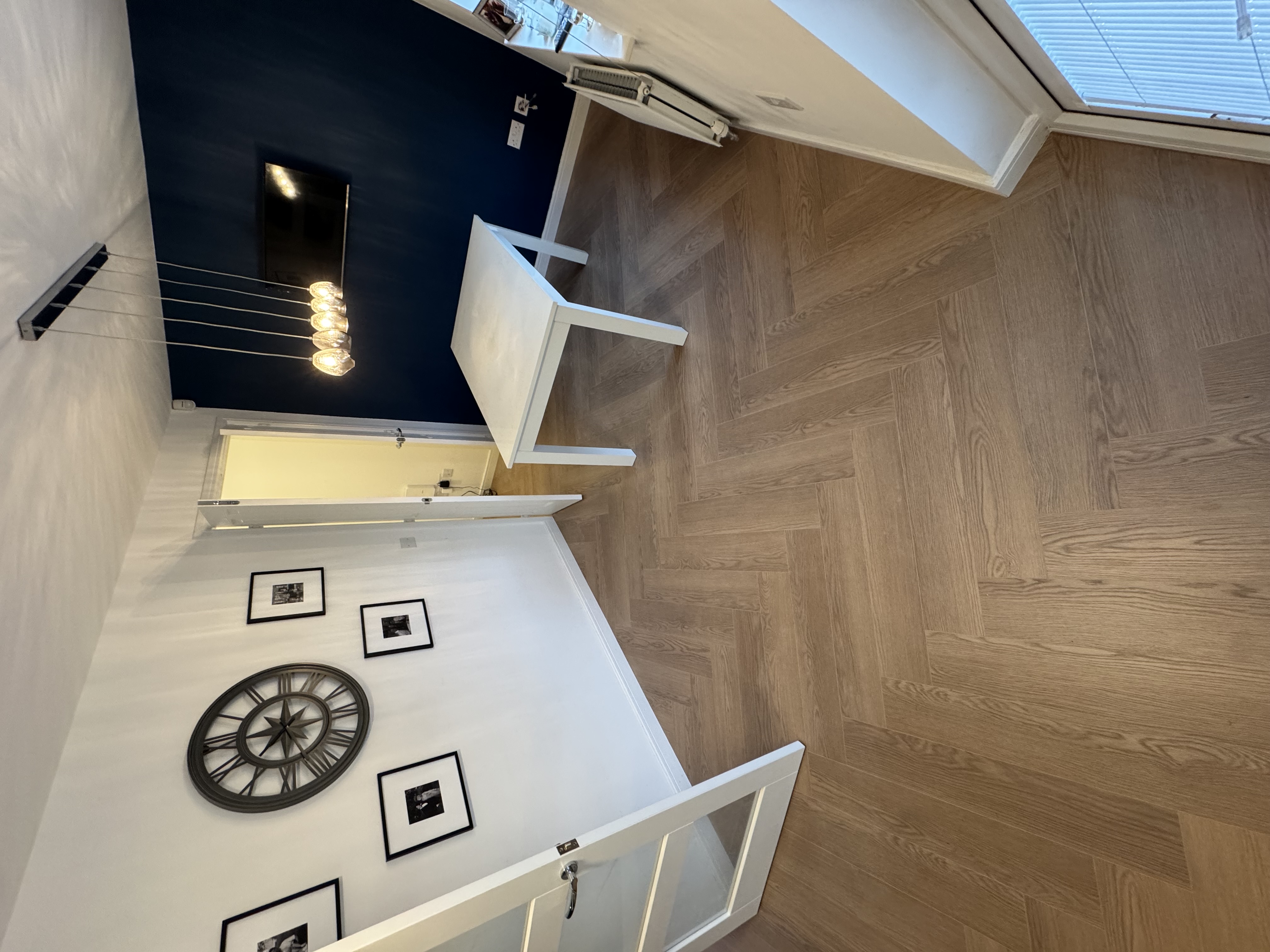 Herringbone flooring in a dining room with navy feature wall