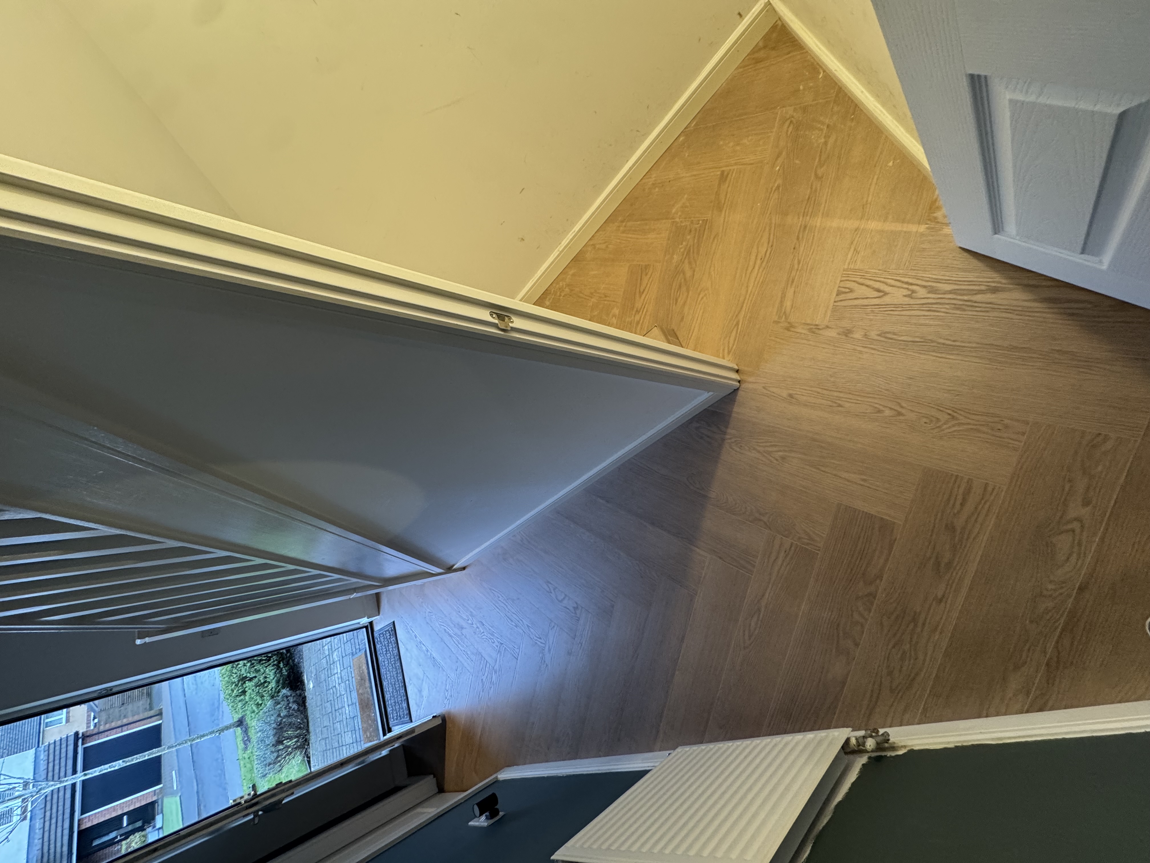 Dark herringbone flooring in a hallway with bay window