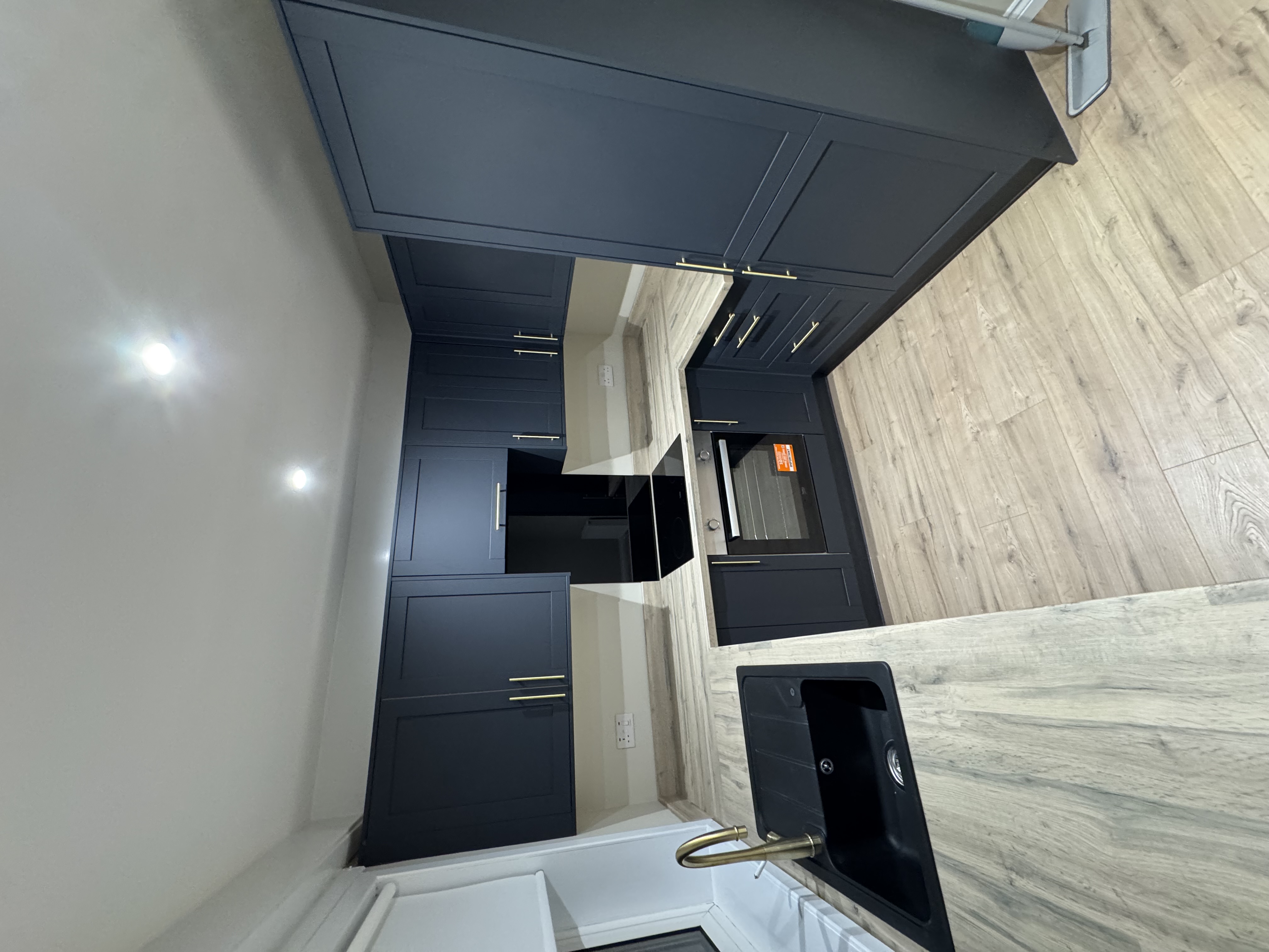 Navy kitchen with black sink and gold tap